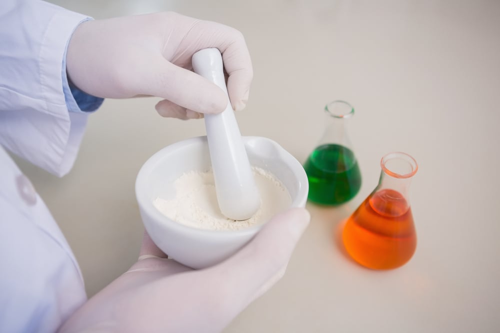 Technician grinding a chemical powder with a mortar and pestle to reduce particle size