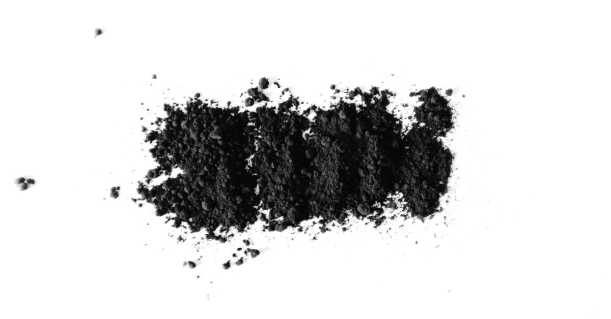 Pile of dark graphite-like powder on a white surface